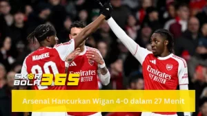 Dua pemain Arsenal mengenakan jersey merah-putih (Emirates Better) sedang melakukan selebrasi 'high five' atau mengangkat tangan bersama di lapangan; terlihat Noni Madueke (nomor 20) dari arah belakang dan rekan setimnya di depan kerumunan penonton yang buram; terdapat logo SKORBOLA365 kuning di pojok kiri bawah dan teks "Arsenal Hancurkan Wigan 4-0 dalam 27 Menit" pada bilah kuning di bagian bawah.