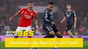 Dua pemain sepak bola sedang berduel memperebutkan bola di lapangan; pemain Real Madrid mengenakan jersey biru gelap (navy) sedang menggiring bola, sementara pemain Benfica berjersey merah berusaha membayangi; terdapat logo SKORBOLA365 di sisi kanan bawah dan teks "Liga Champions : Prediksi Real Madrid vs Benfica 18 Februari 2026" pada bilah biru cerah di bagian bawah.